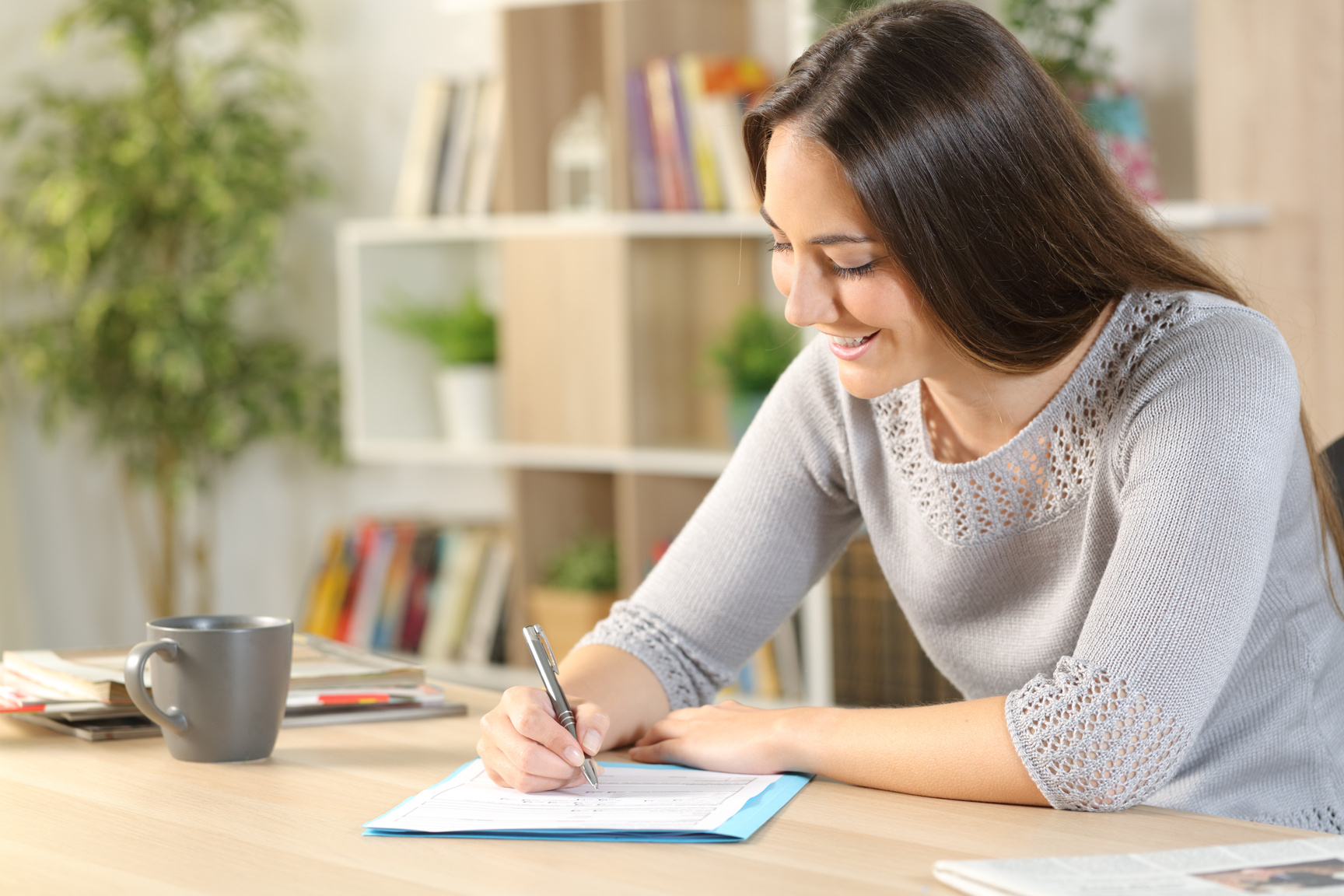Happy woman filling out form on a desk at home